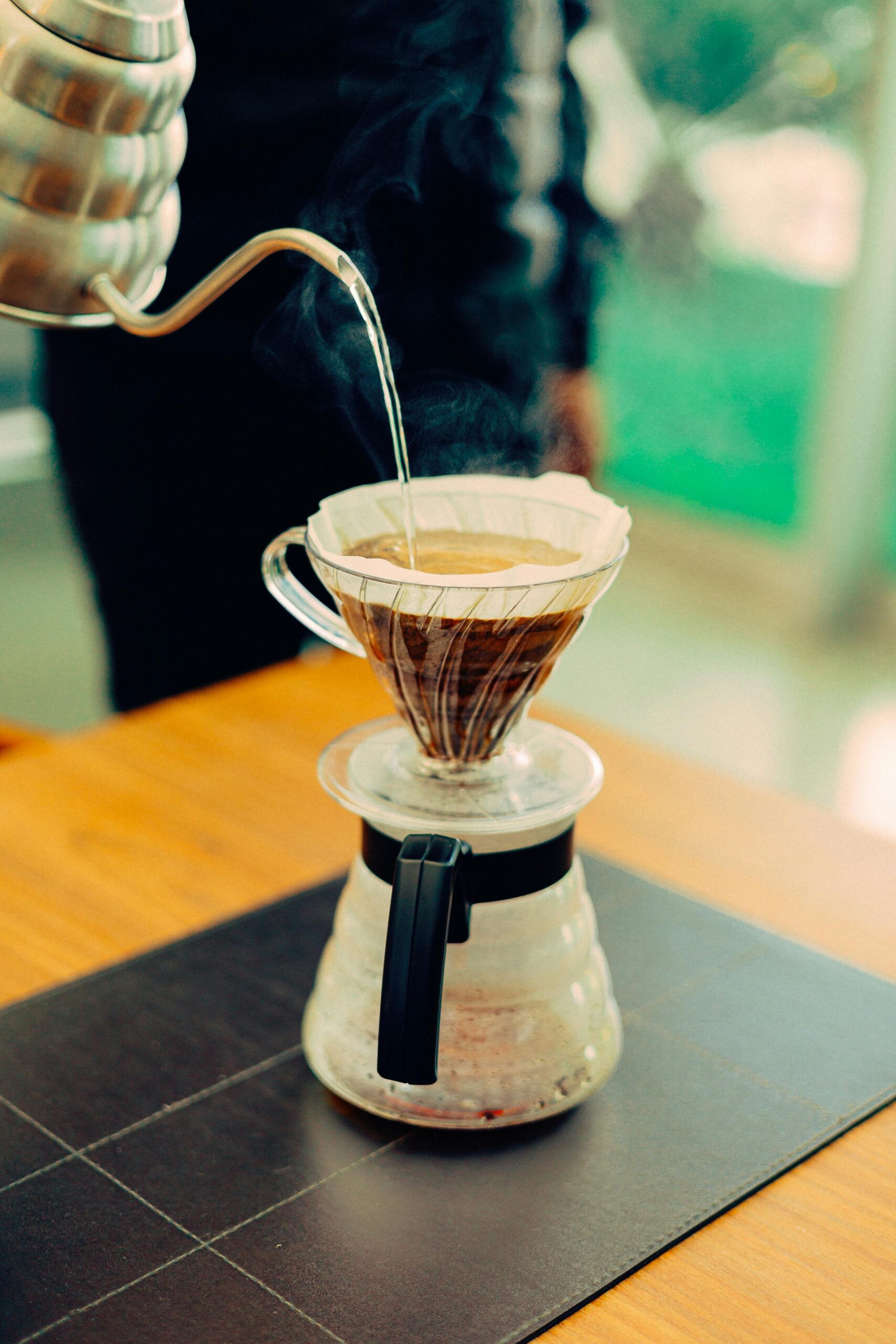 Close-up of hot water being poured into a filter coffee maker with steam rising.